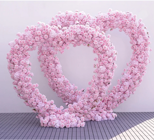Heart-shaped arrangement of pink flowers on a white background with Weddingstoryshop 