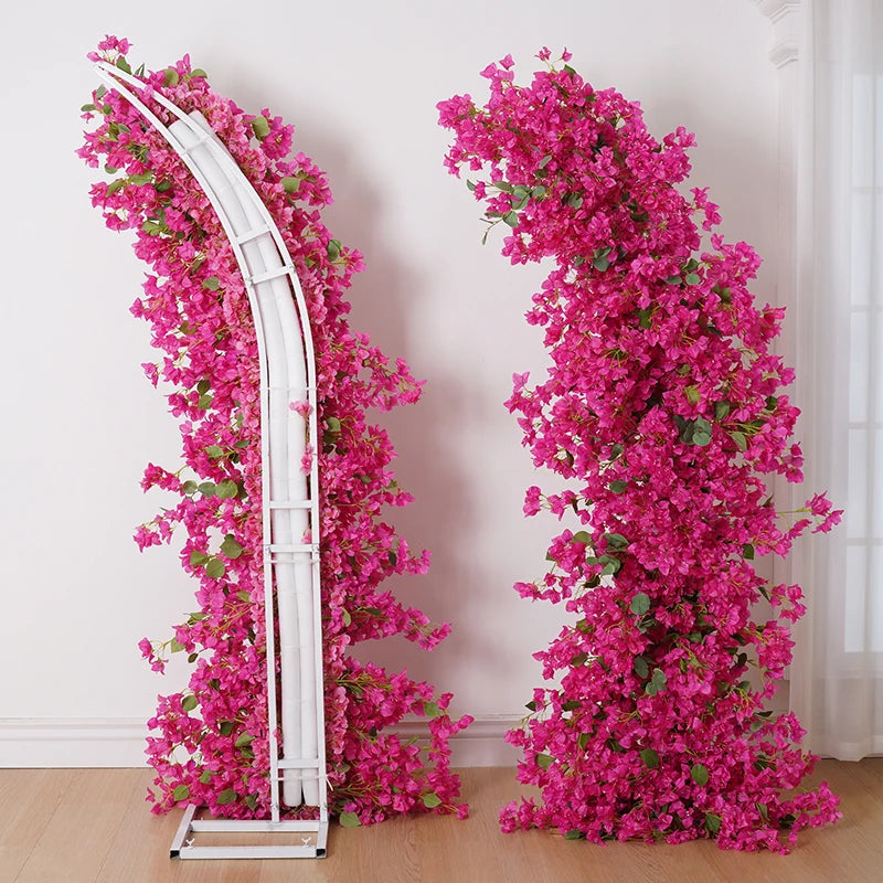 Decorative arch with pink artificial flowers against a white wall