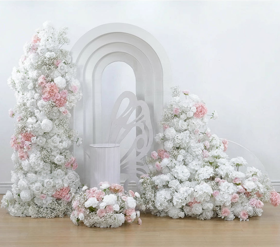 Floral archway with white and pink flowers in front of a decorative white arch