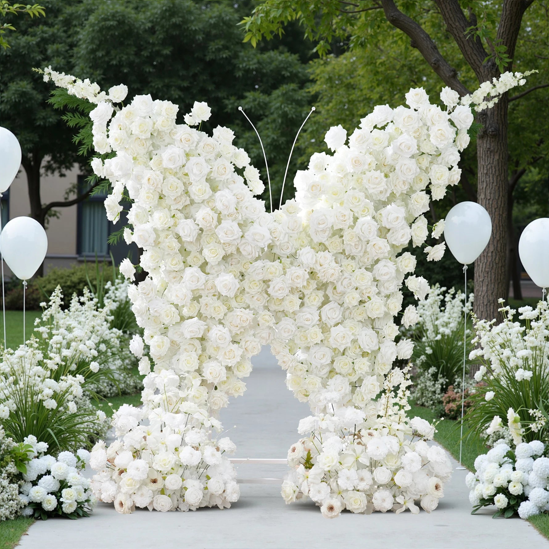 Floral arch made of white flowers with balloons on a pathway