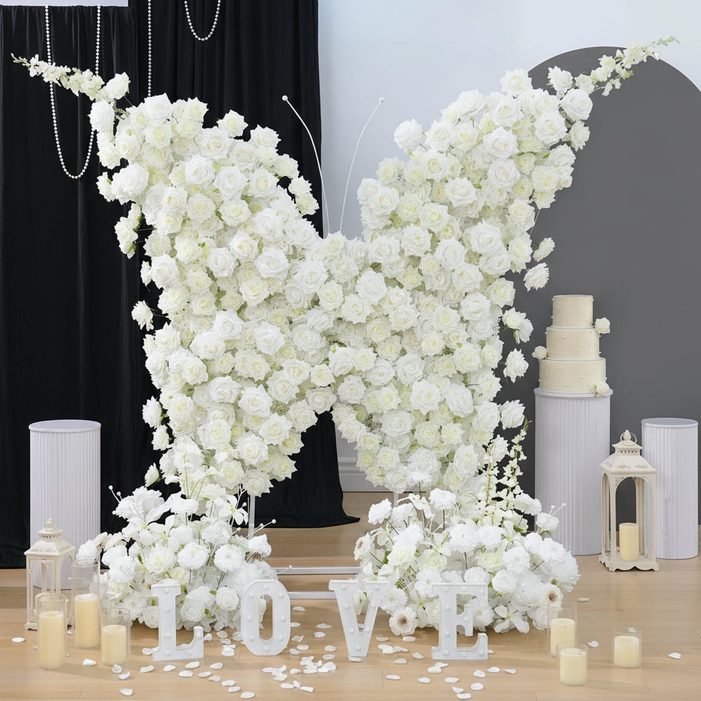 White floral arch with 'LOVE' letters and candles on a wooden floor, branded 'Angela Flower'.