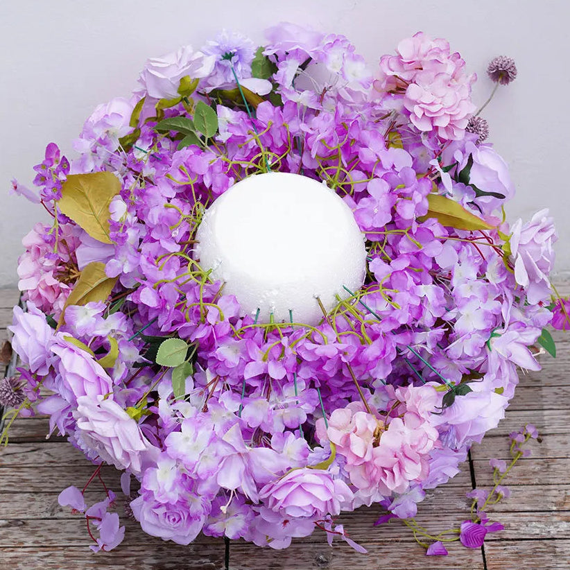 Floral wreath with pink and purple flowers on a wooden surface